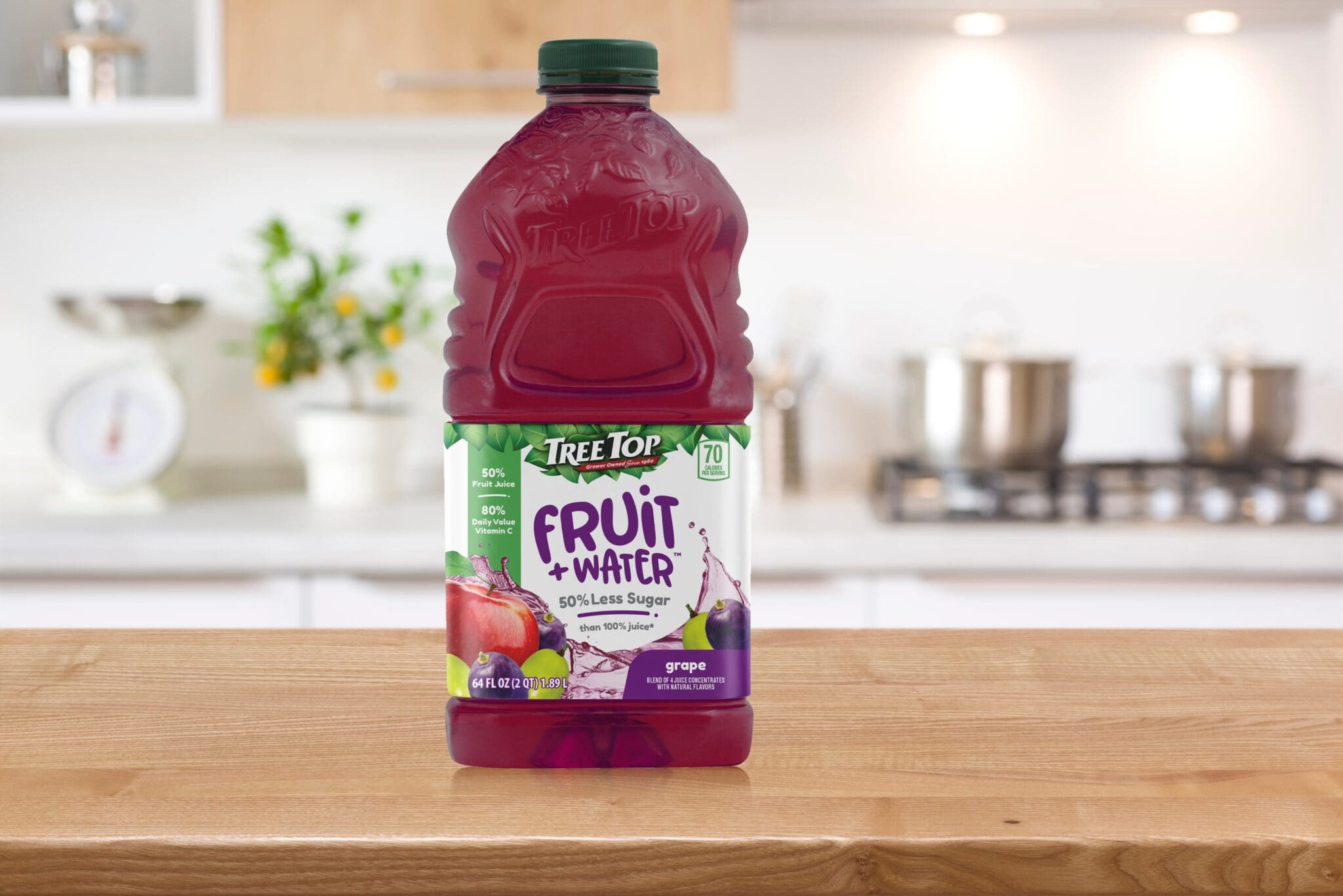 Bottle of Tree Top Fruit + Water grape juice centered on kitchen counter with blurred background.