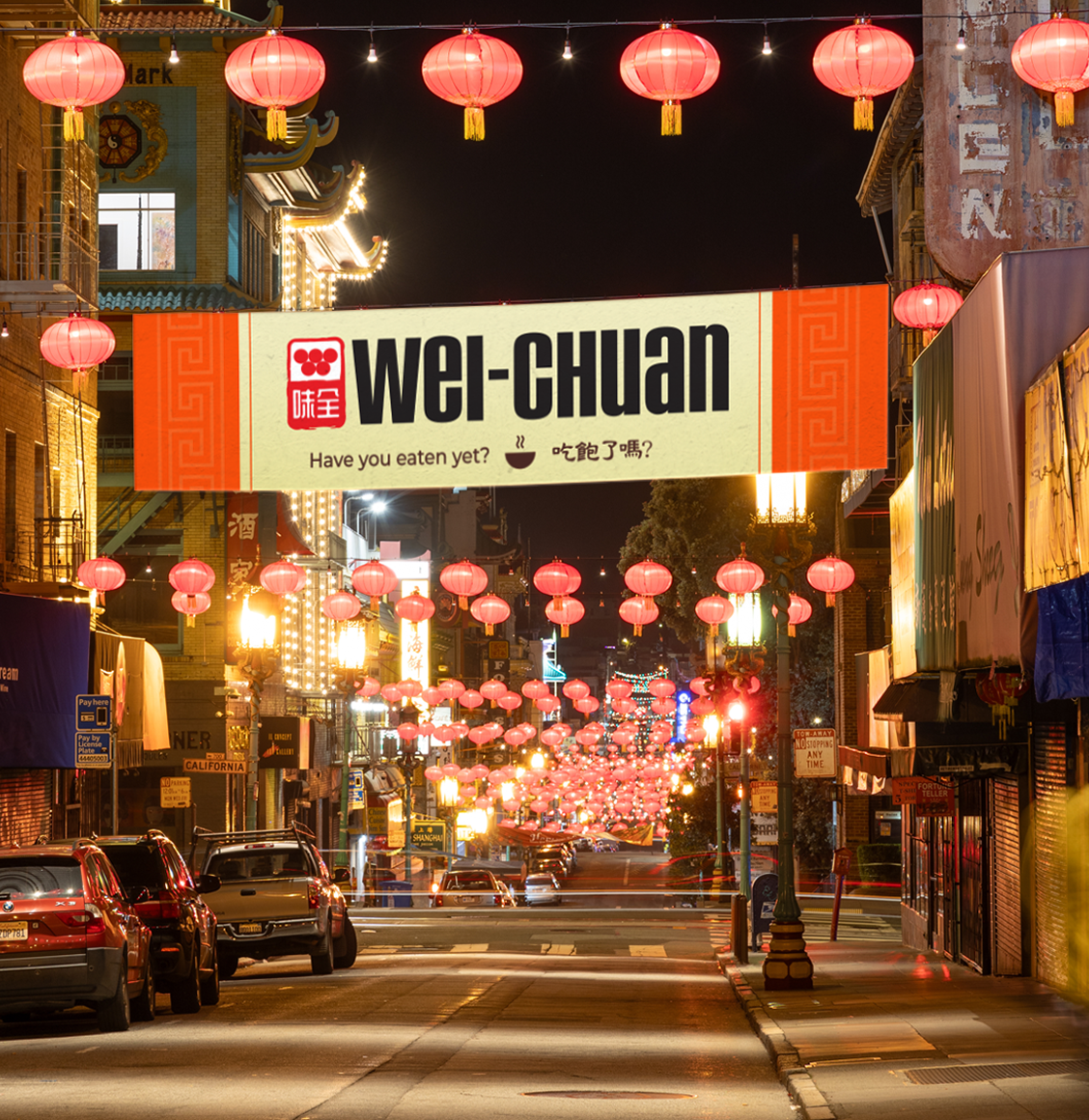 Night street scene with red Chinese lanterns and a large Wei-Chuan banner spanning the road, festive lights overhead, and cars parked along the curb.