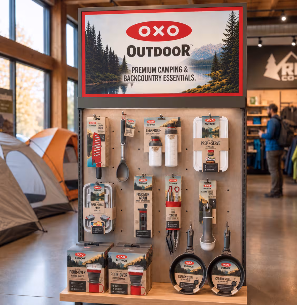 Oxo Outdoor camping gear on a pegboard display in a store, with utensils, pans, and prep kits ready for purchase.