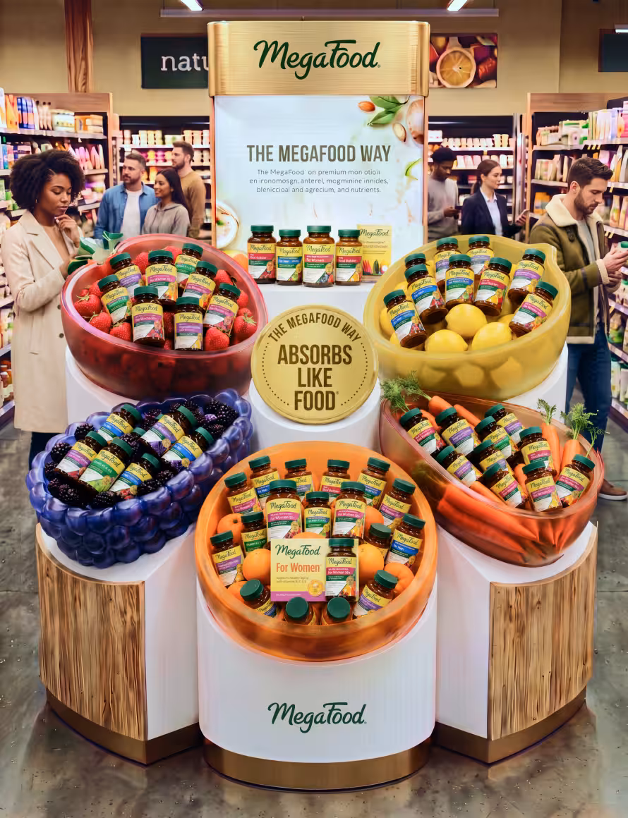 Megafood display in a grocery store with five colorful fruit-shaped bowls full of MegaFood bottles and a central banner reading 'The MegaFood Way'.